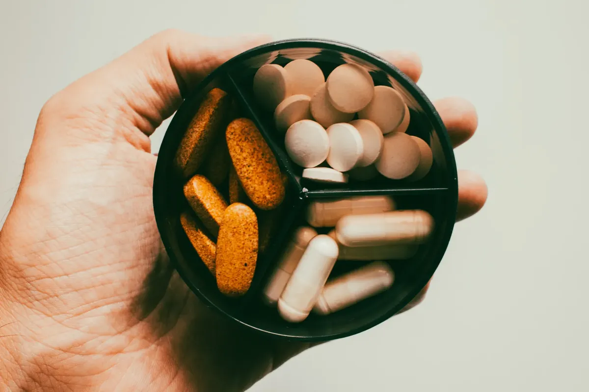 Close-up of a hand holding different types of supplements and vitamins.