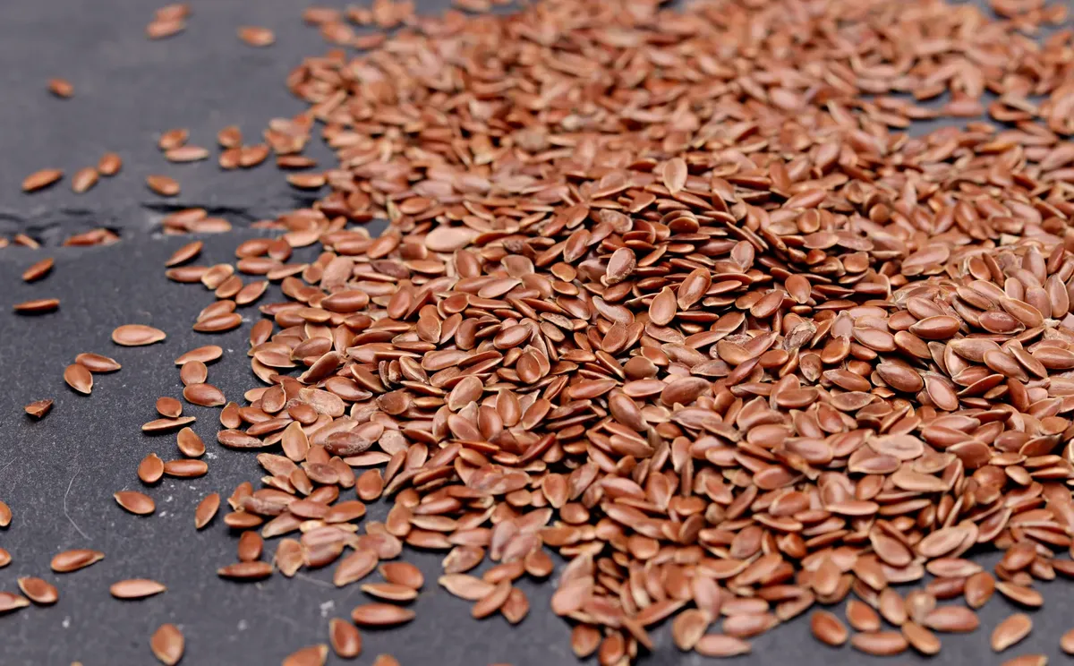 High-resolution close-up of nutritious flaxseeds scattered on a dark background, perfect for health and diet concepts.